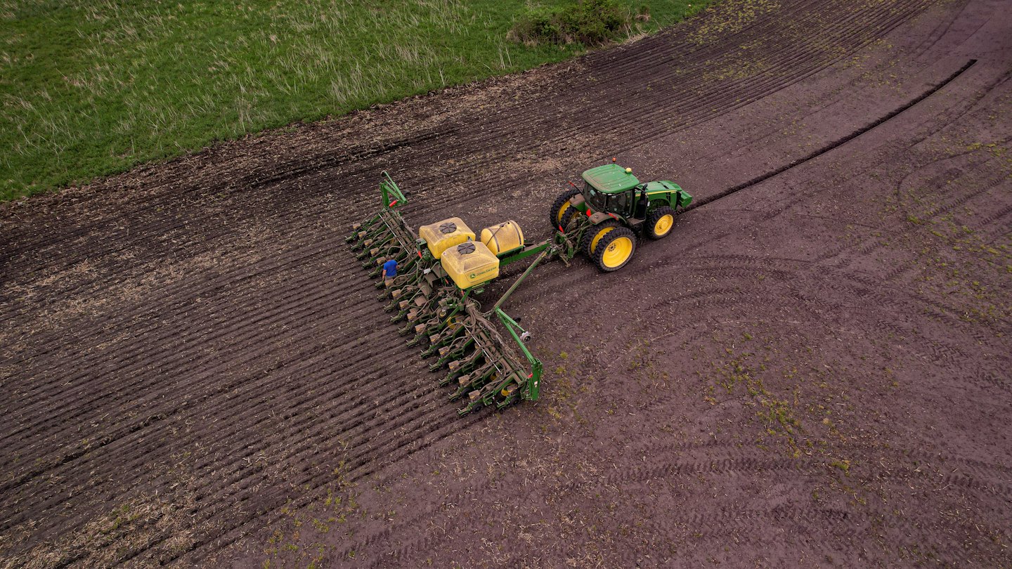 Farmer driving a tractor to plant crops in a field.